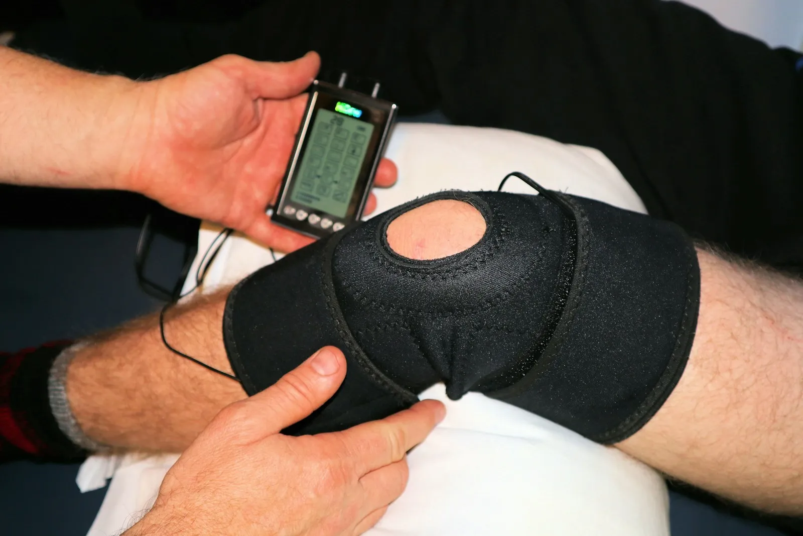 Elettrostimolatore portatile collegato a una fascia con elettrodi sul ginocchio